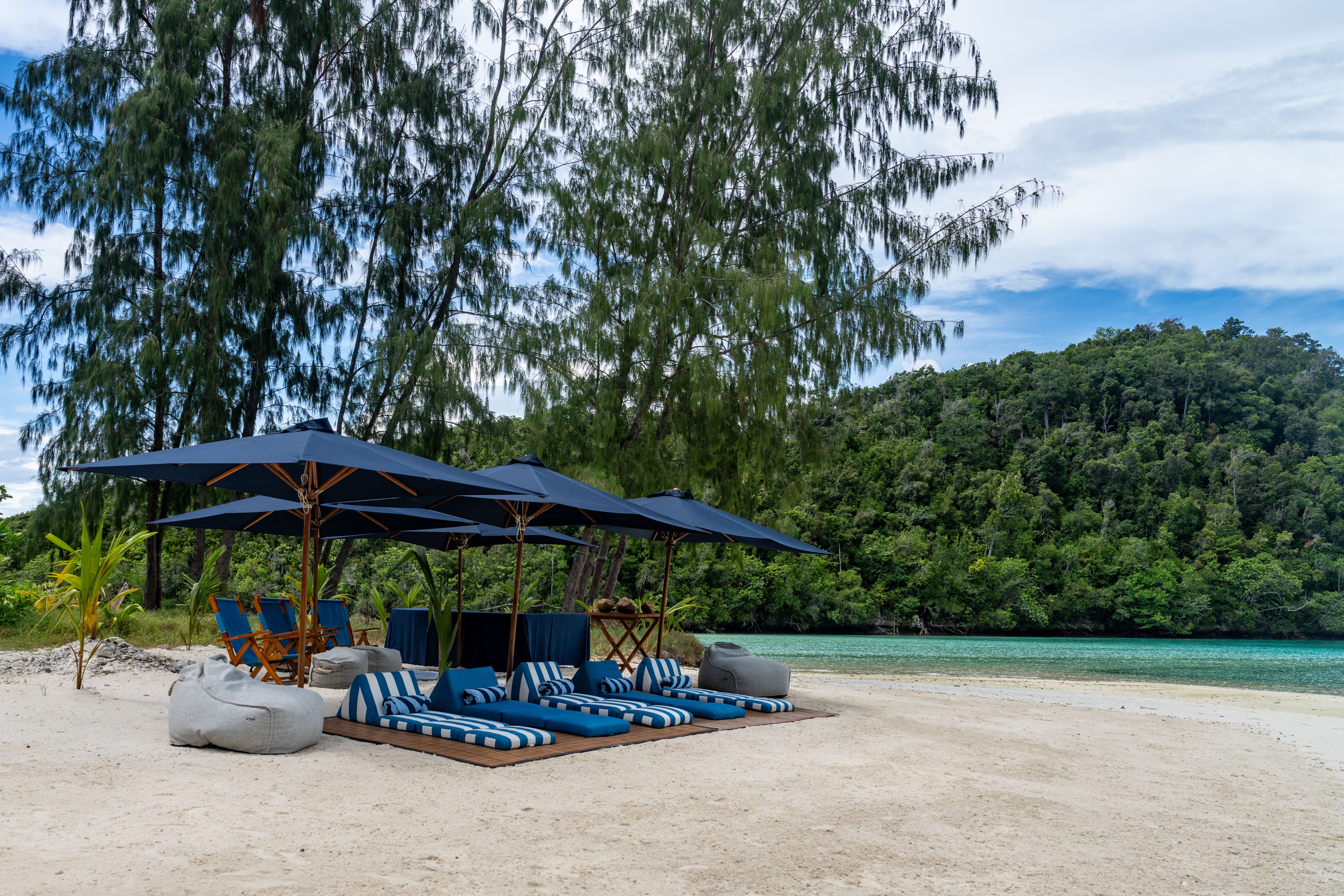 Blue parasols and striped loungers set out on a white beach