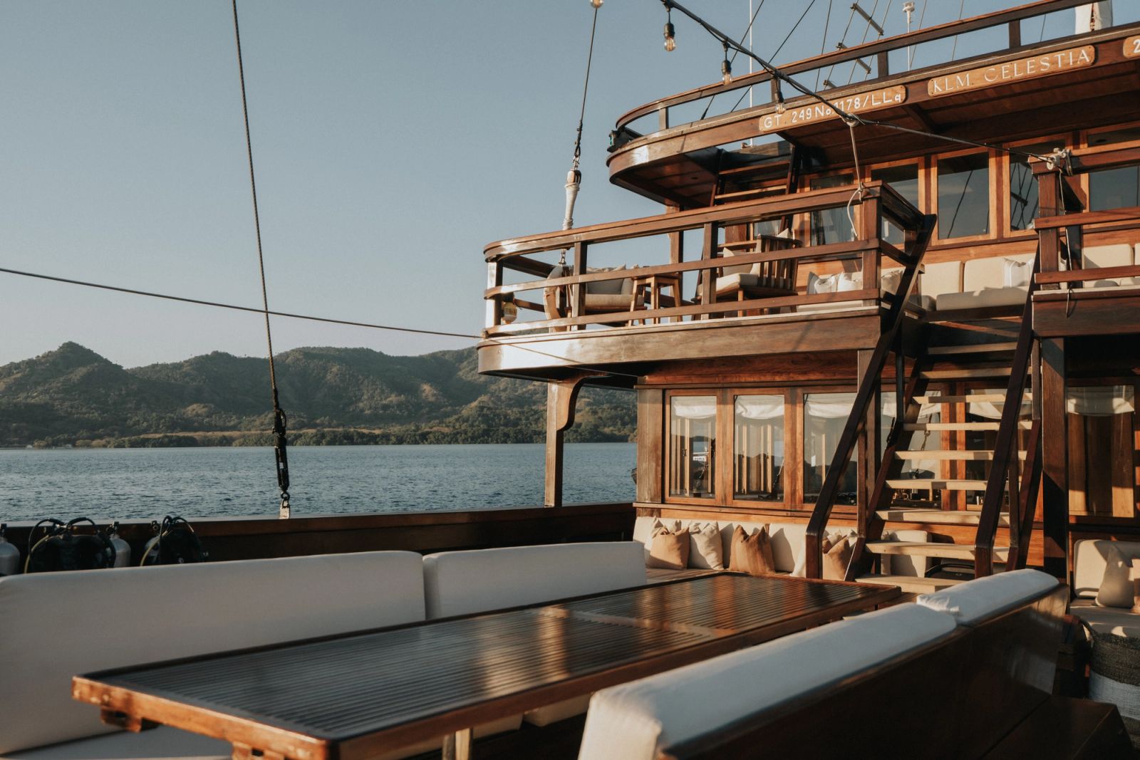 The deck lounge and upper deck stairs of Celestia with green hills beyond.