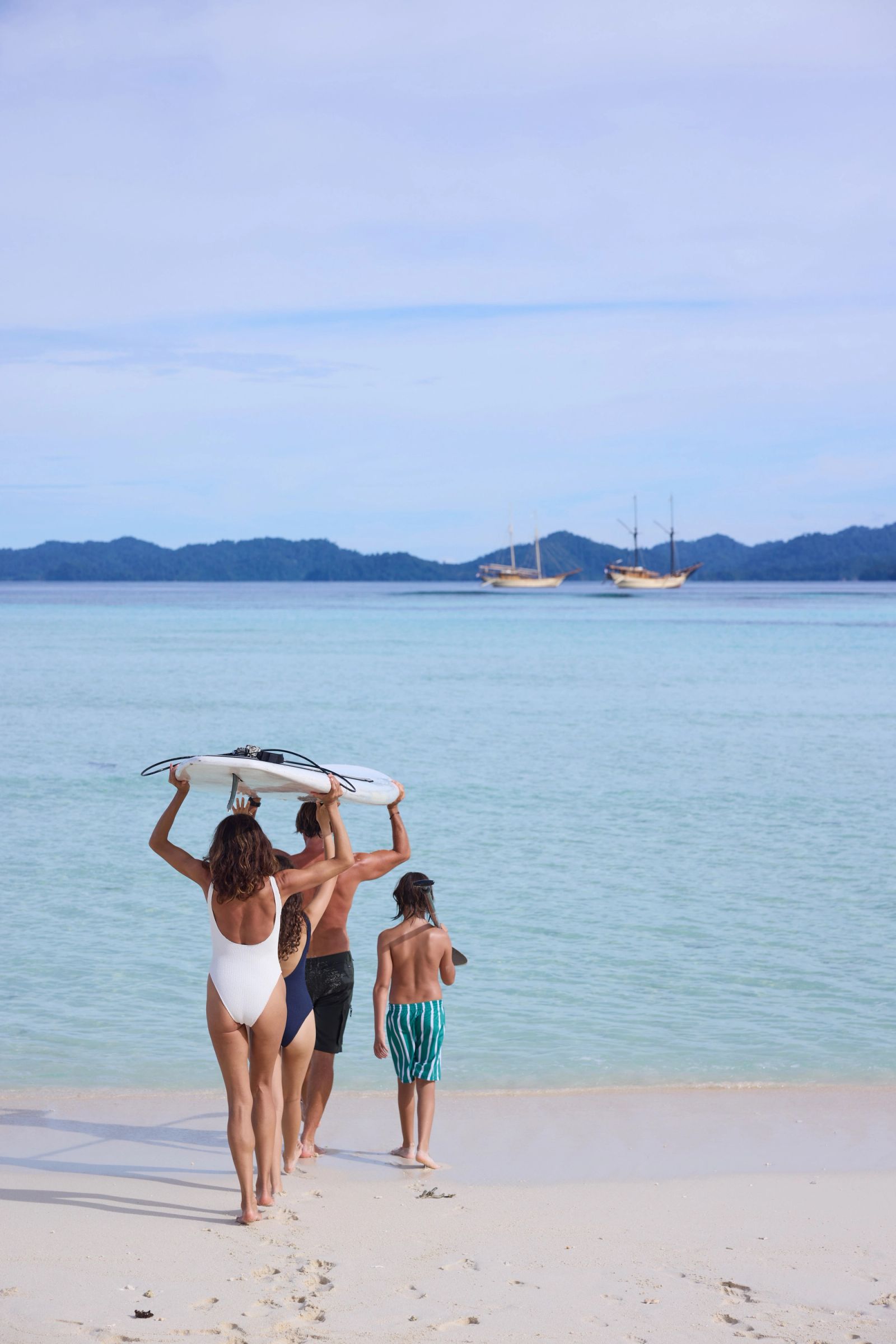 A family walking into the sea with boards beside Silolona