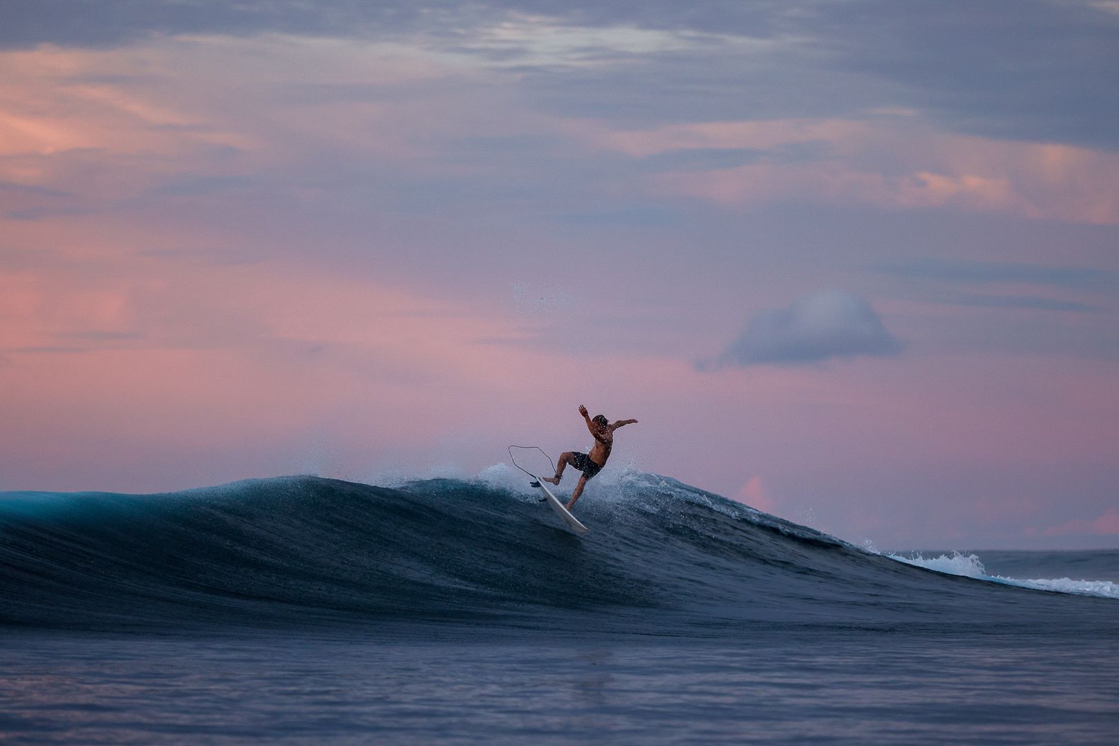 A surfer carving a clean wave at dusk