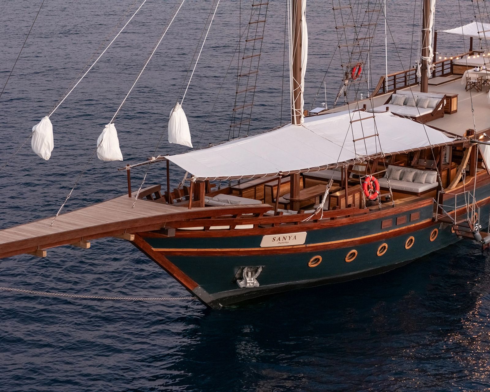 An aerial view of the bow and dark blue hull of Sanya at anchor.