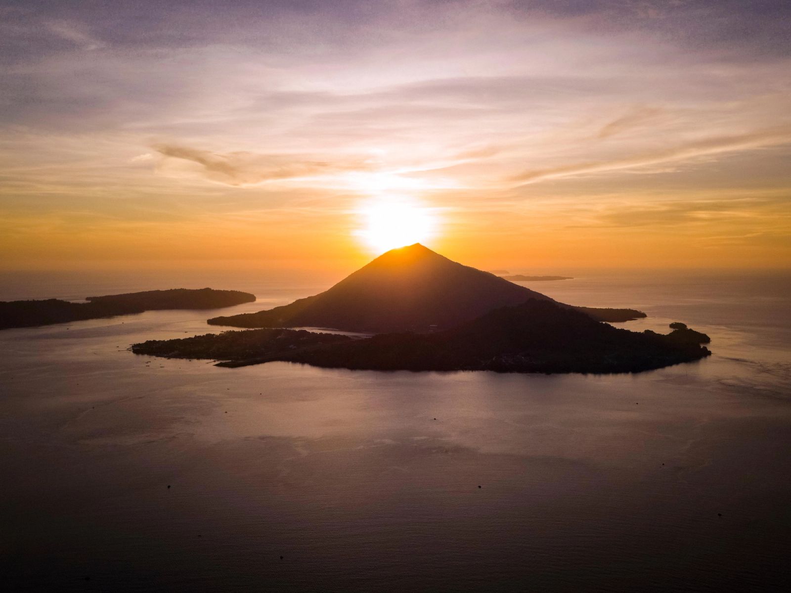 The sun setting behind a volcanic island in the Banda Sea