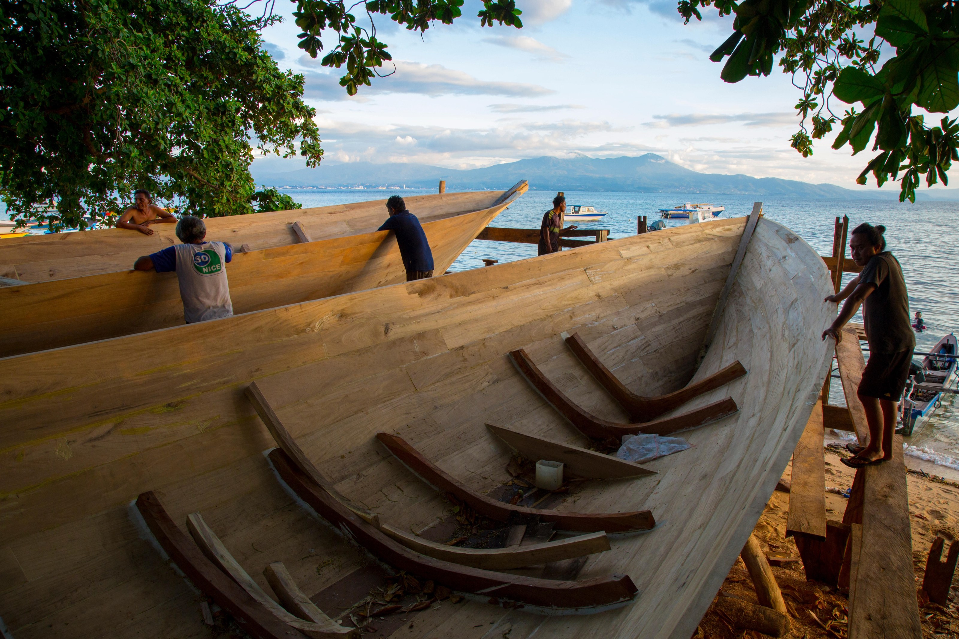 Boat builders at work on a hull on the beach