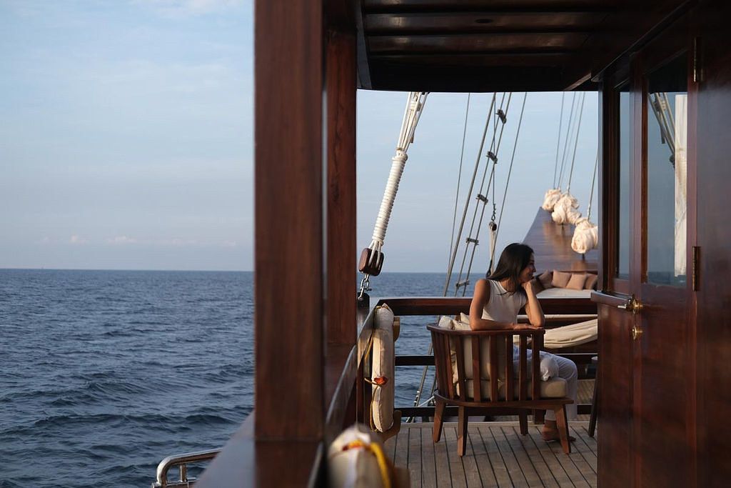 A woman seated at a table on the covered deck of Celestia looking out to sea.