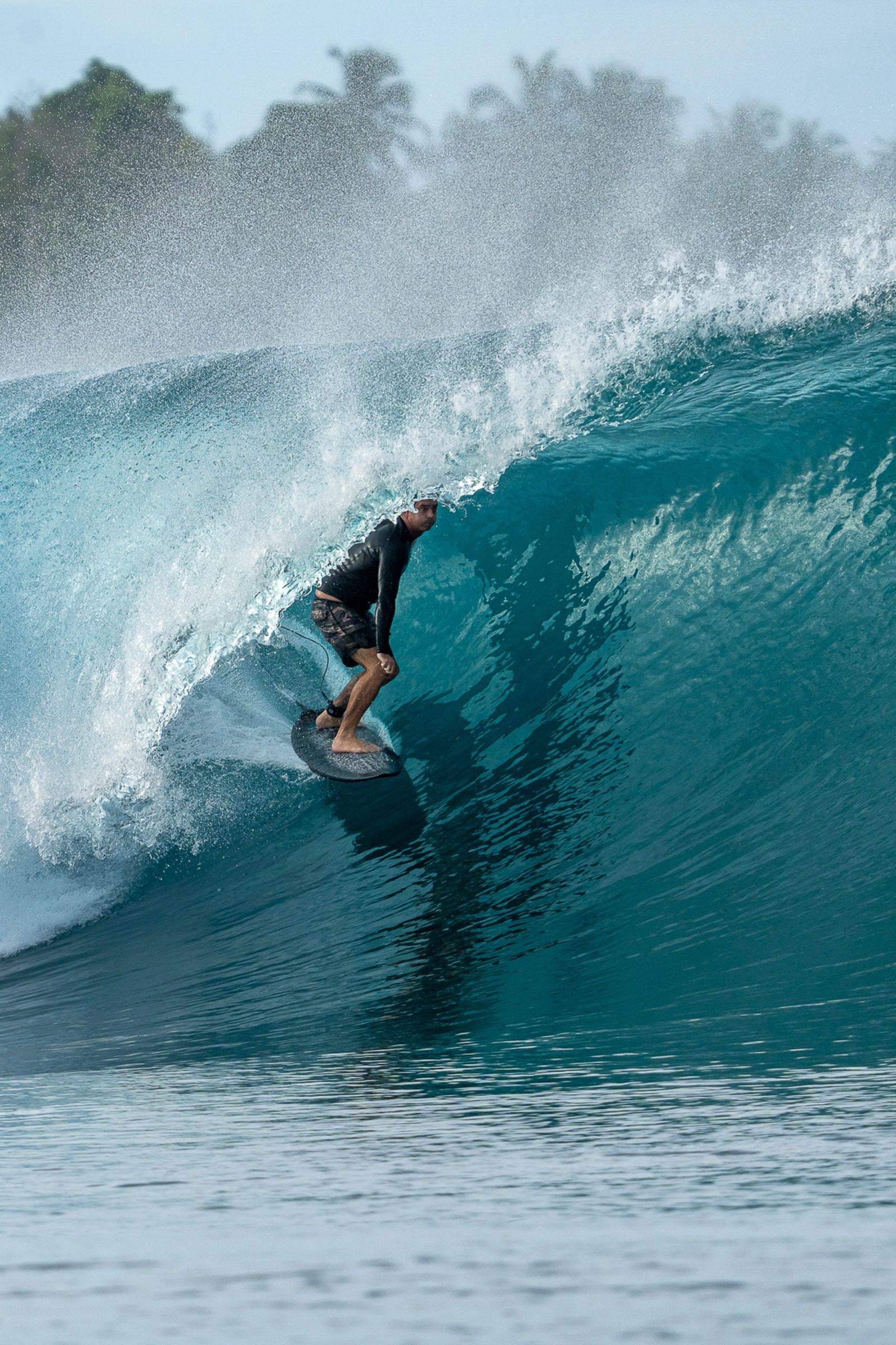A surfer inside a turquoise barrel.