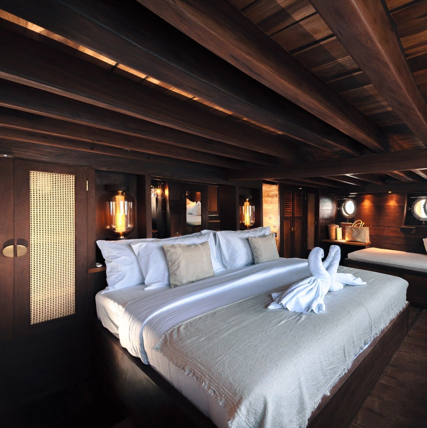 A guest cabin on Nataraja with folded towels on a wide bed.