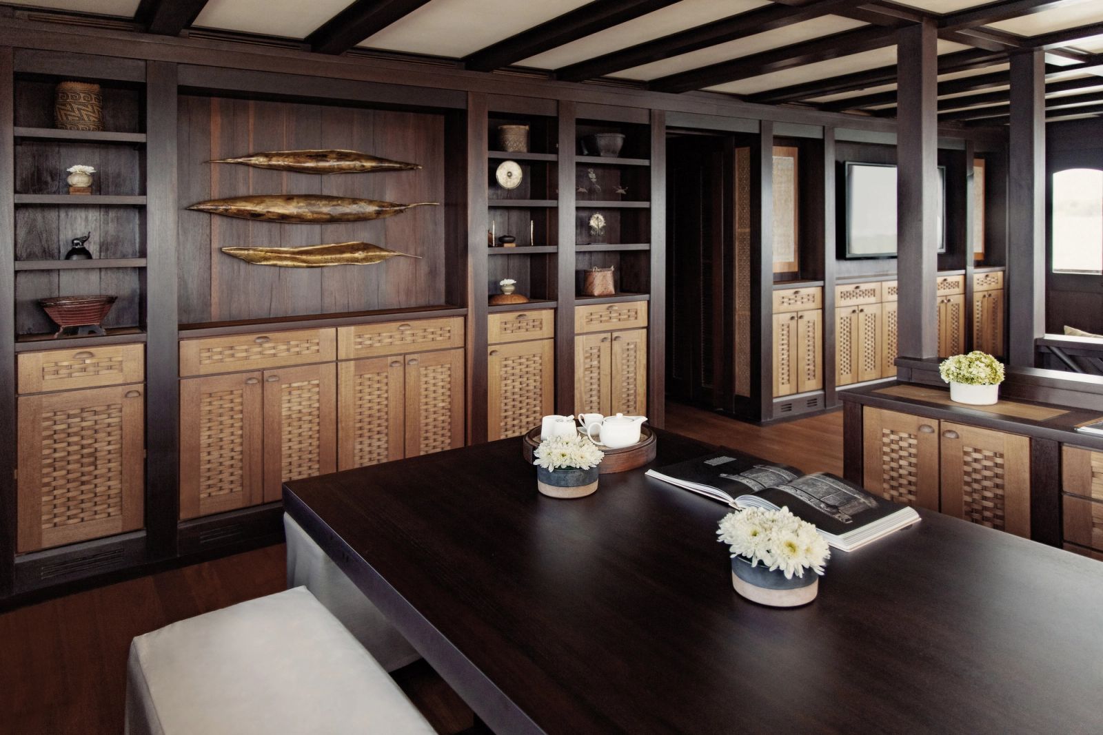 Dunia Baru's saloon with a dining table and timber shelving