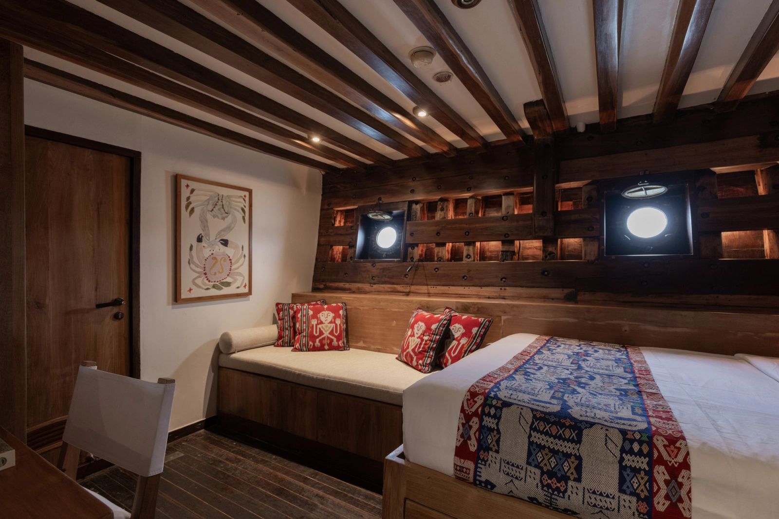 A guest cabin on El Aleph with a daybed and a bed beneath glowing porthole niches.