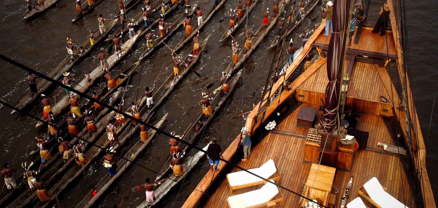 An Asmat canoe flotilla welcoming the schooner in West Papua