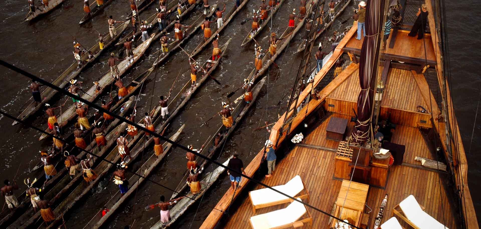 An Asmat canoe flotilla welcoming the schooner in West Papua