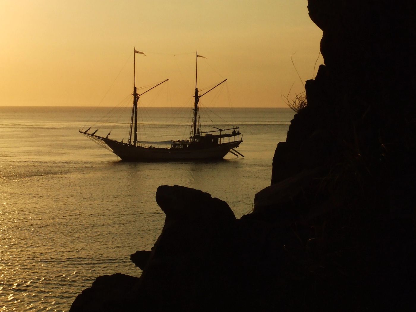Silolona's silhouette at dusk beyond a sea cliff