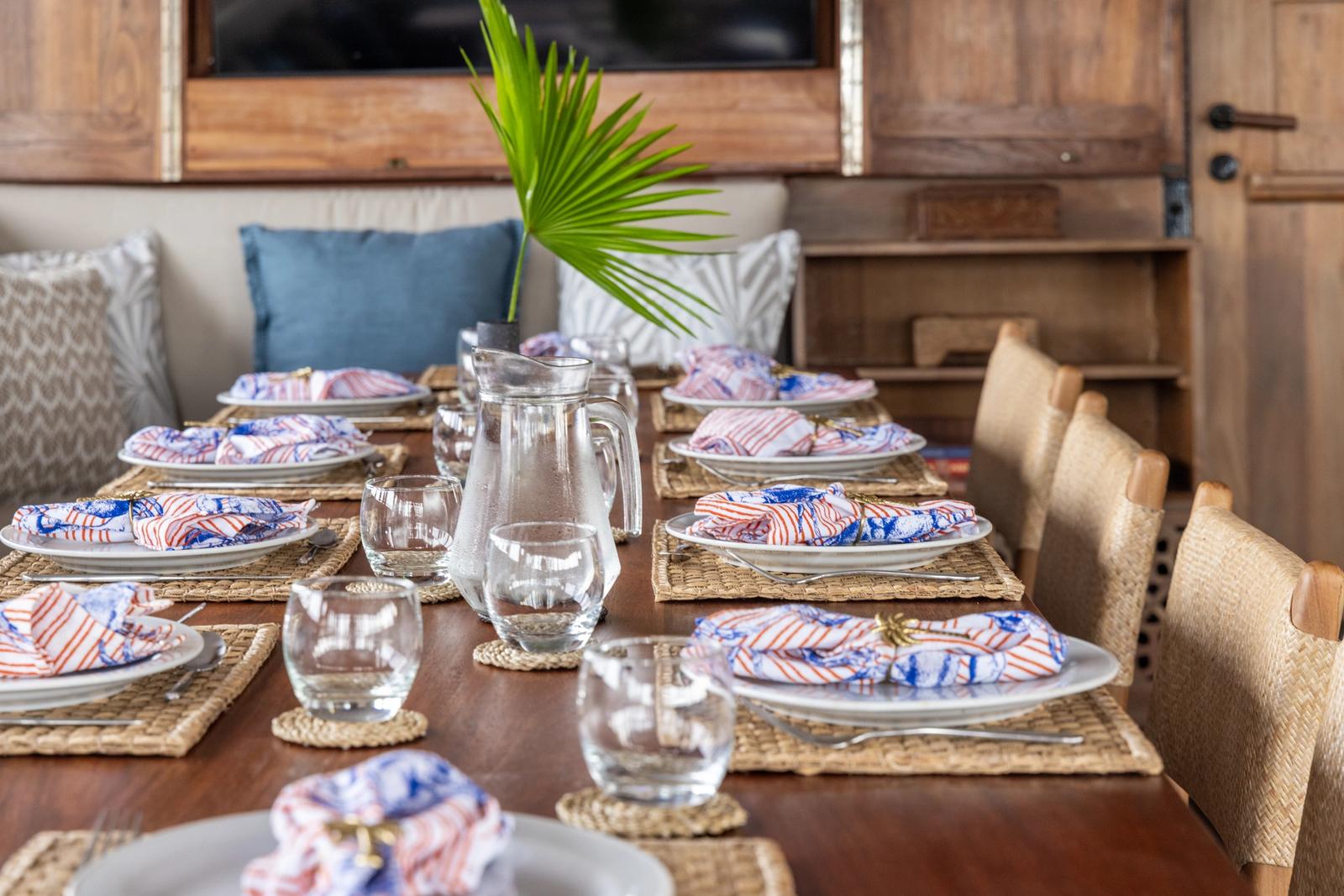 A dining table set with plates and glasses in a wood-panelled saloon