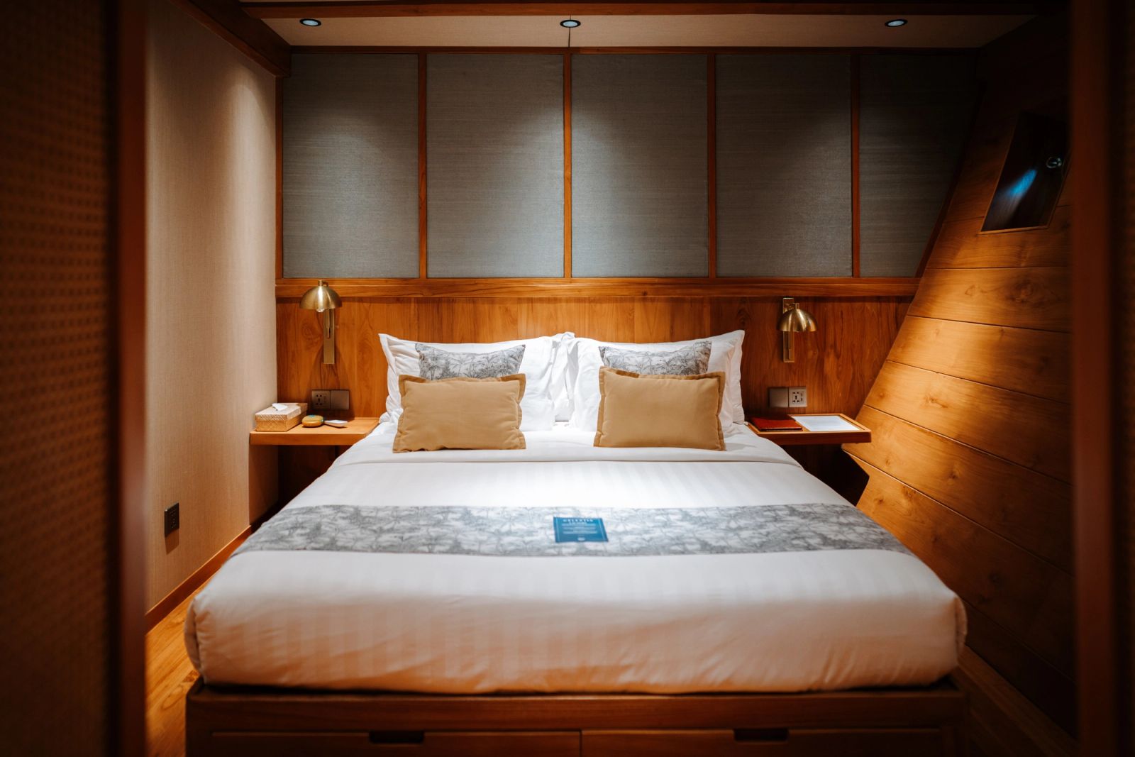 A queen stateroom on Celestia with a bed set beneath paneled walls.