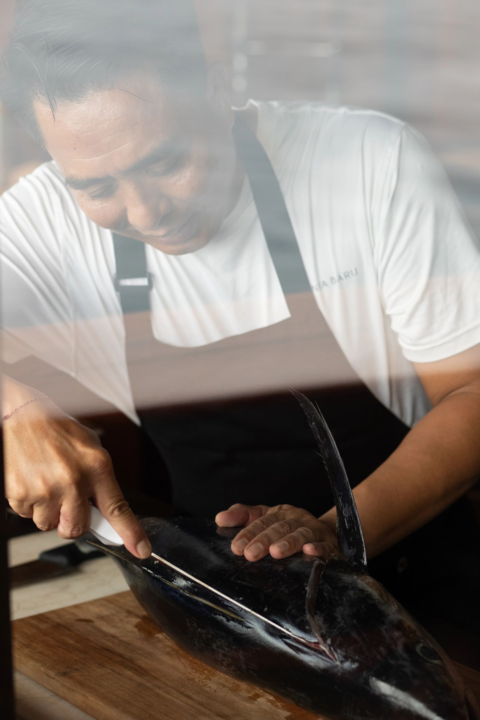 A chef filleting fresh fish in Dunia Baru's galley