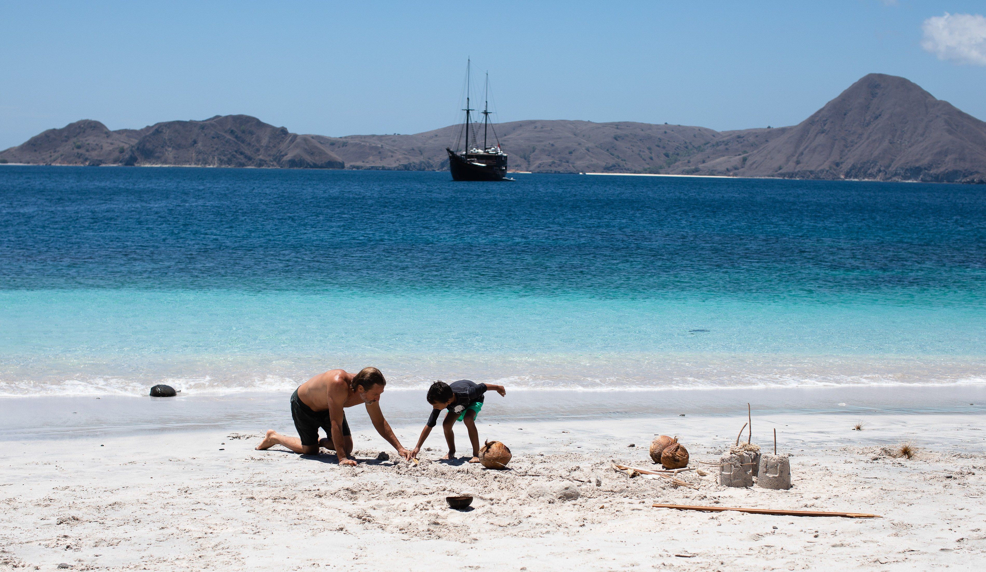 Sandcastles on a quiet beach, with the yacht at anchor offshore.