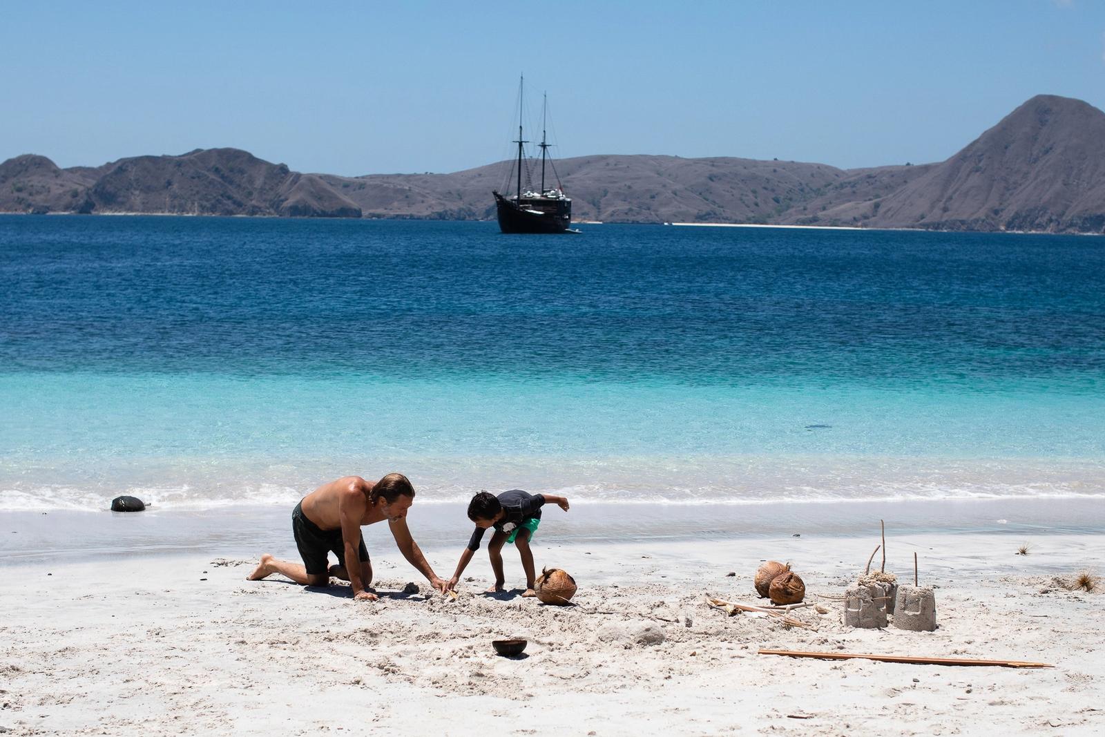 Sandcastles on a quiet beach, with the yacht at anchor offshore.