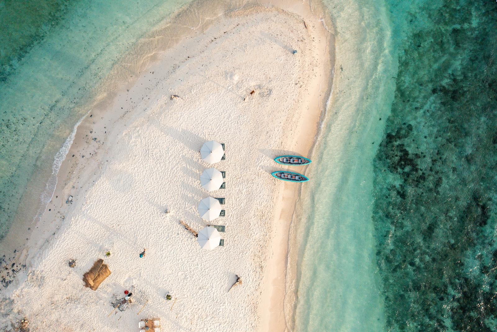 Parasols and jet skis on a white beach, seen from above
