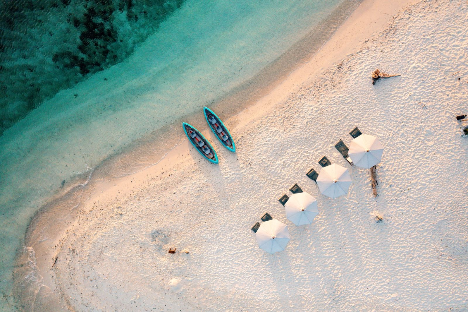 Parasols and kayaks on a white beach, seen from above
