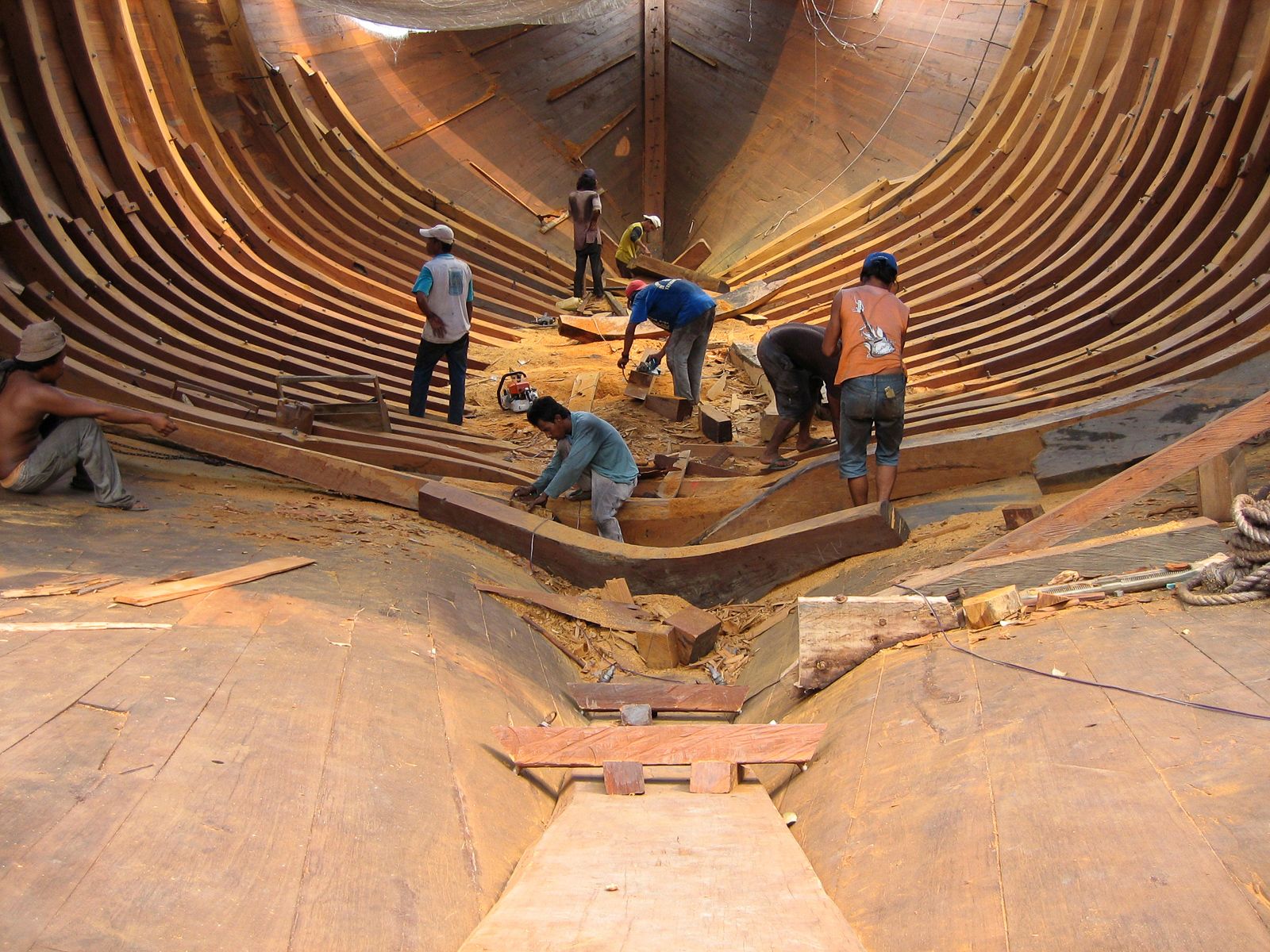 Shipwrights working among a phinisi's wooden frames in the yard