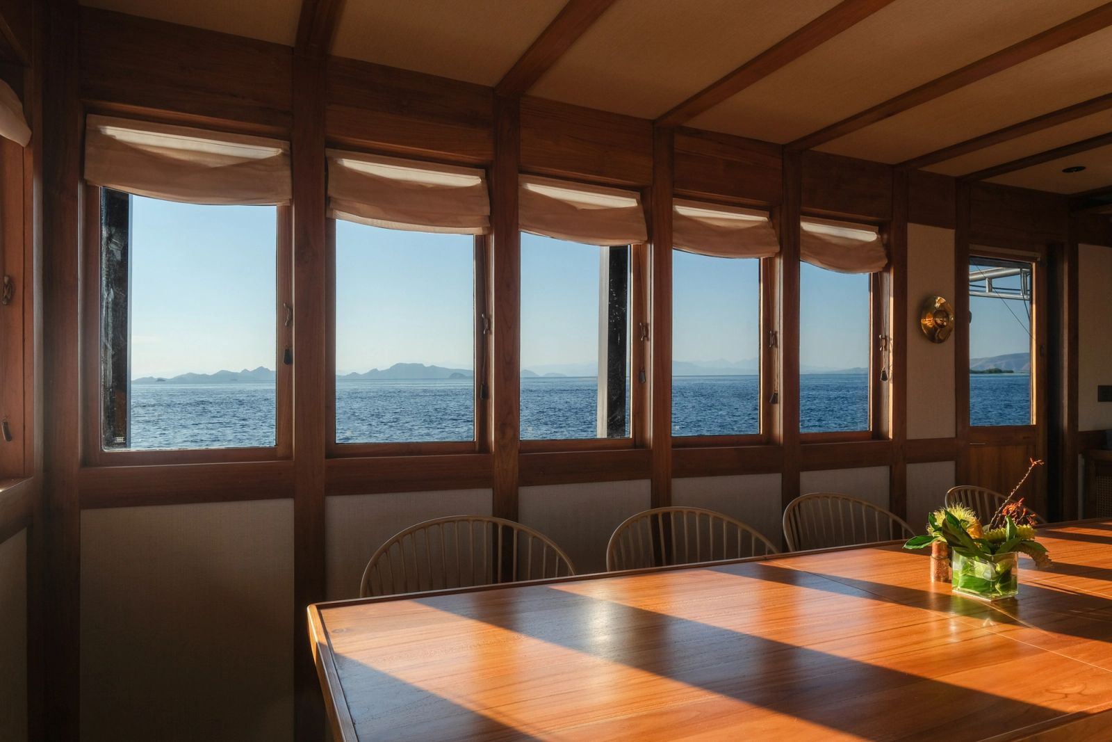 The saloon dining table of Celestia with sea views through the windows.