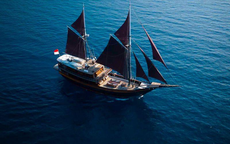 Aerial view of Dunia Baru under full black sails