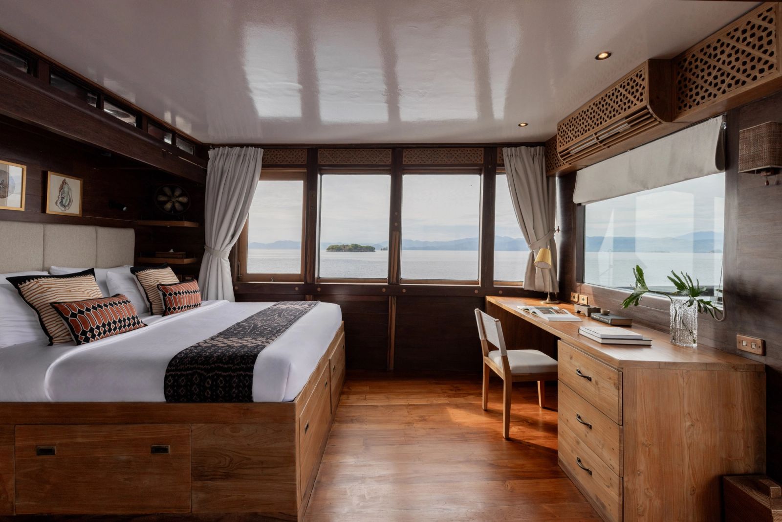 The master cabin on El Aleph with a bed, a desk and a row of windows onto the sea.