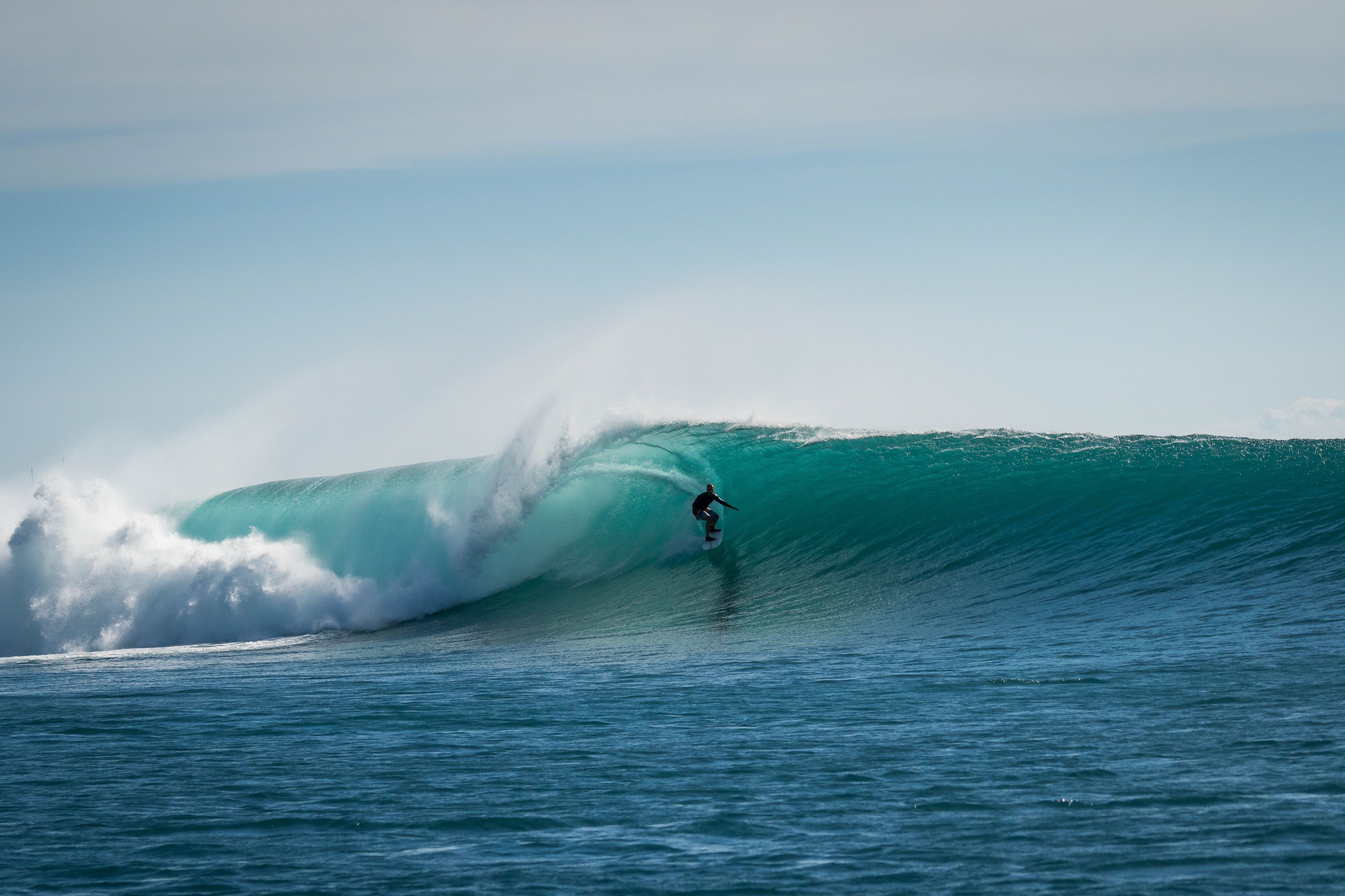 A surfer riding deep inside a turquoise barrel off Sumbawa