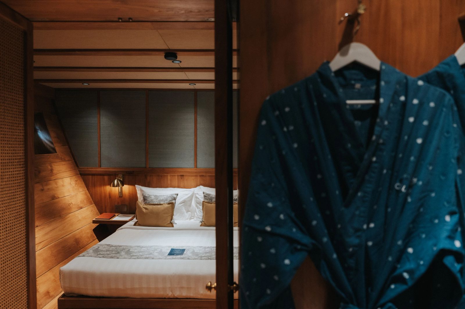 A bathrobe hanging in a queen stateroom on Celestia with the bed beyond.