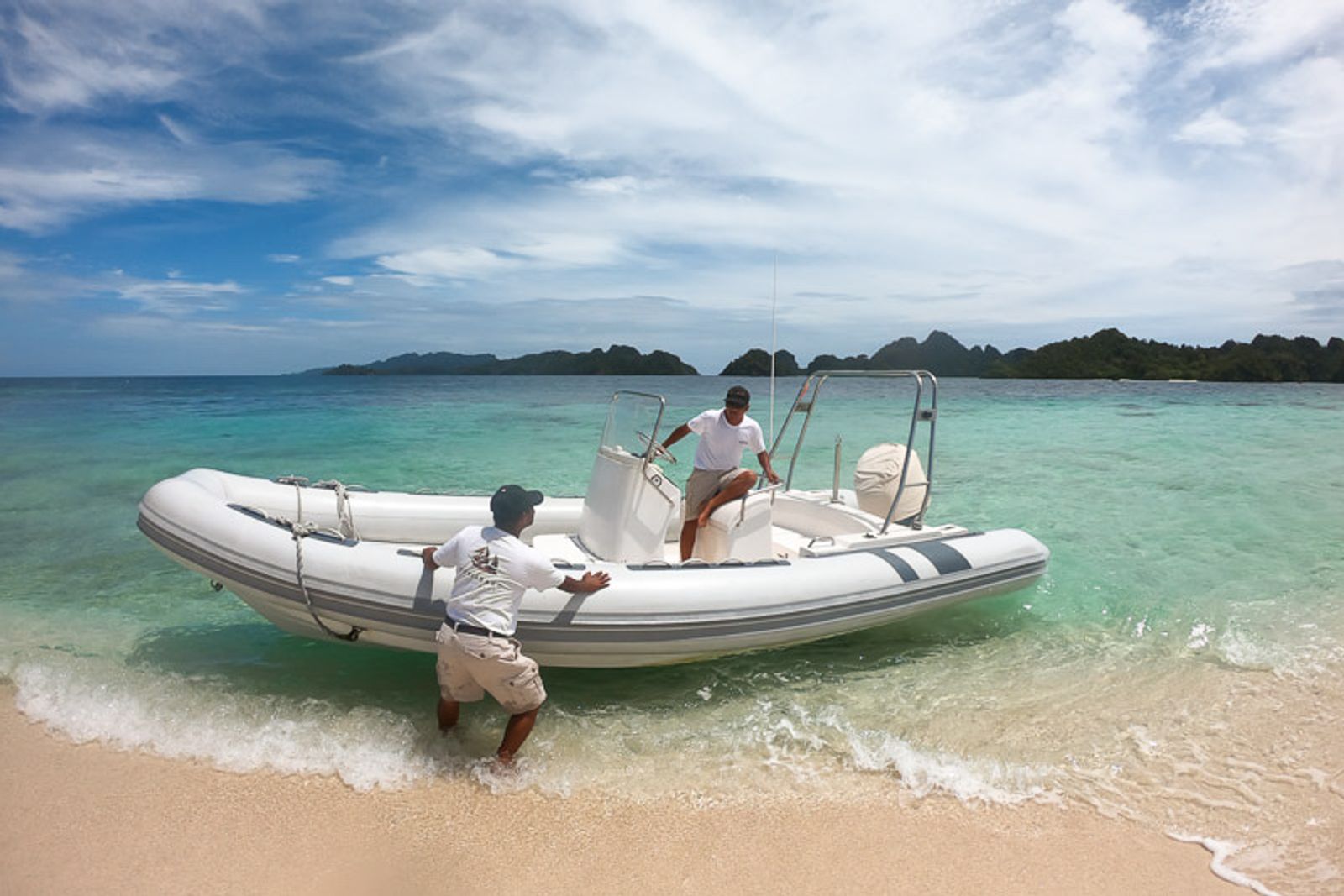 Crew bringing a tender onto a white beach