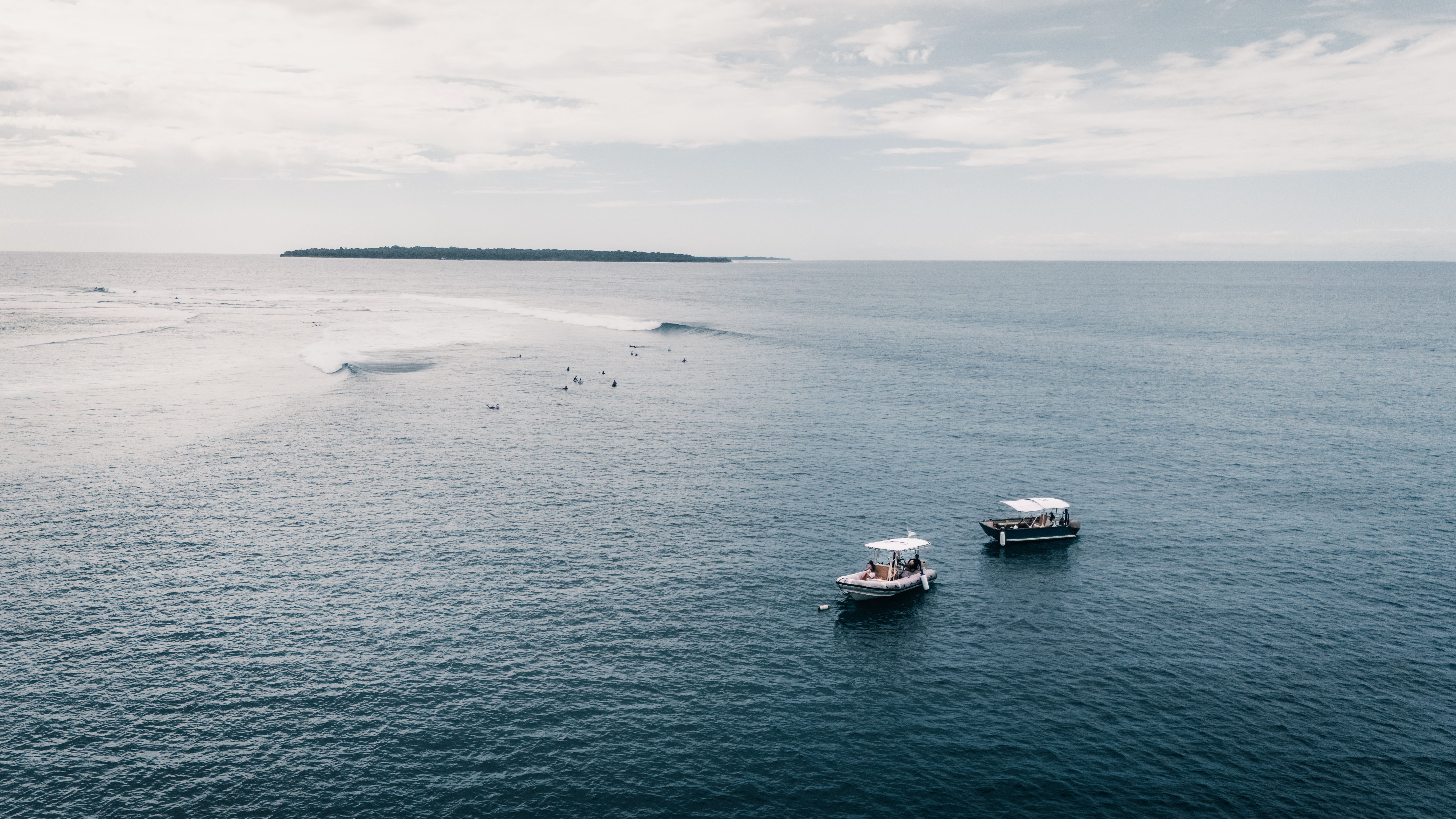 Two boats waiting off a reef break at dawn