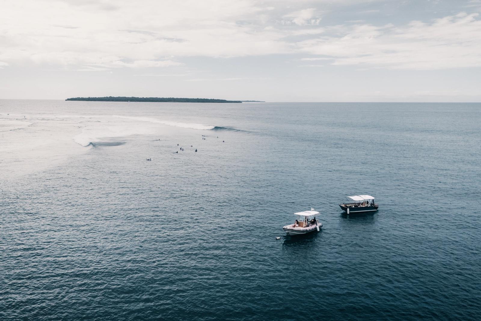 Two boats waiting off a reef break at dawn