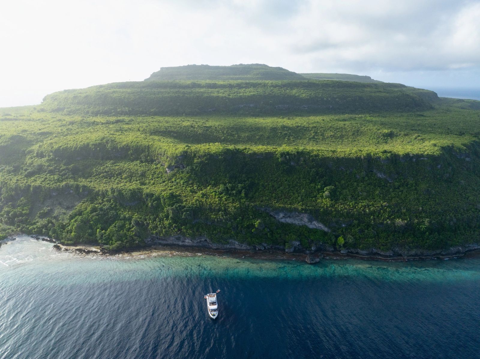 A small ship at anchor off a lone island, the scale of the Forgotten Islands in one frame.