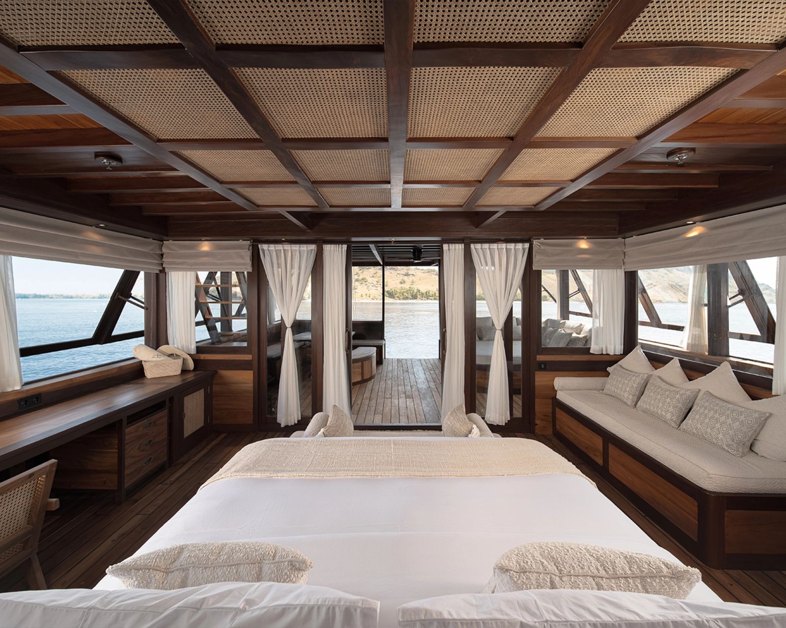 A wide view of the master cabin on Sanya with a king bed between two window seats.