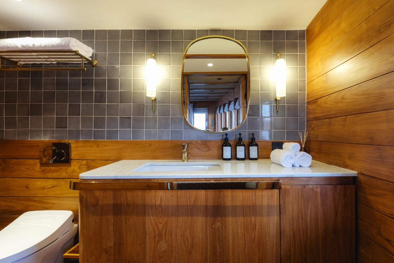 The master bathroom on Celestia with a vanity, round mirror and tiled wall.