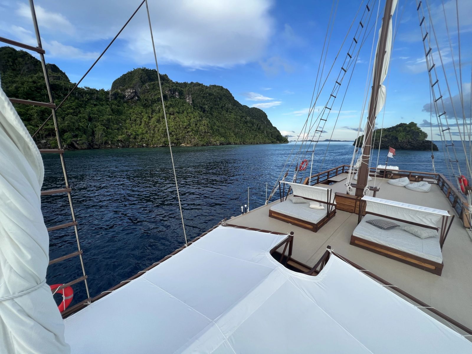 The top deck of Dewata with sunbeds and the island coast beyond.
