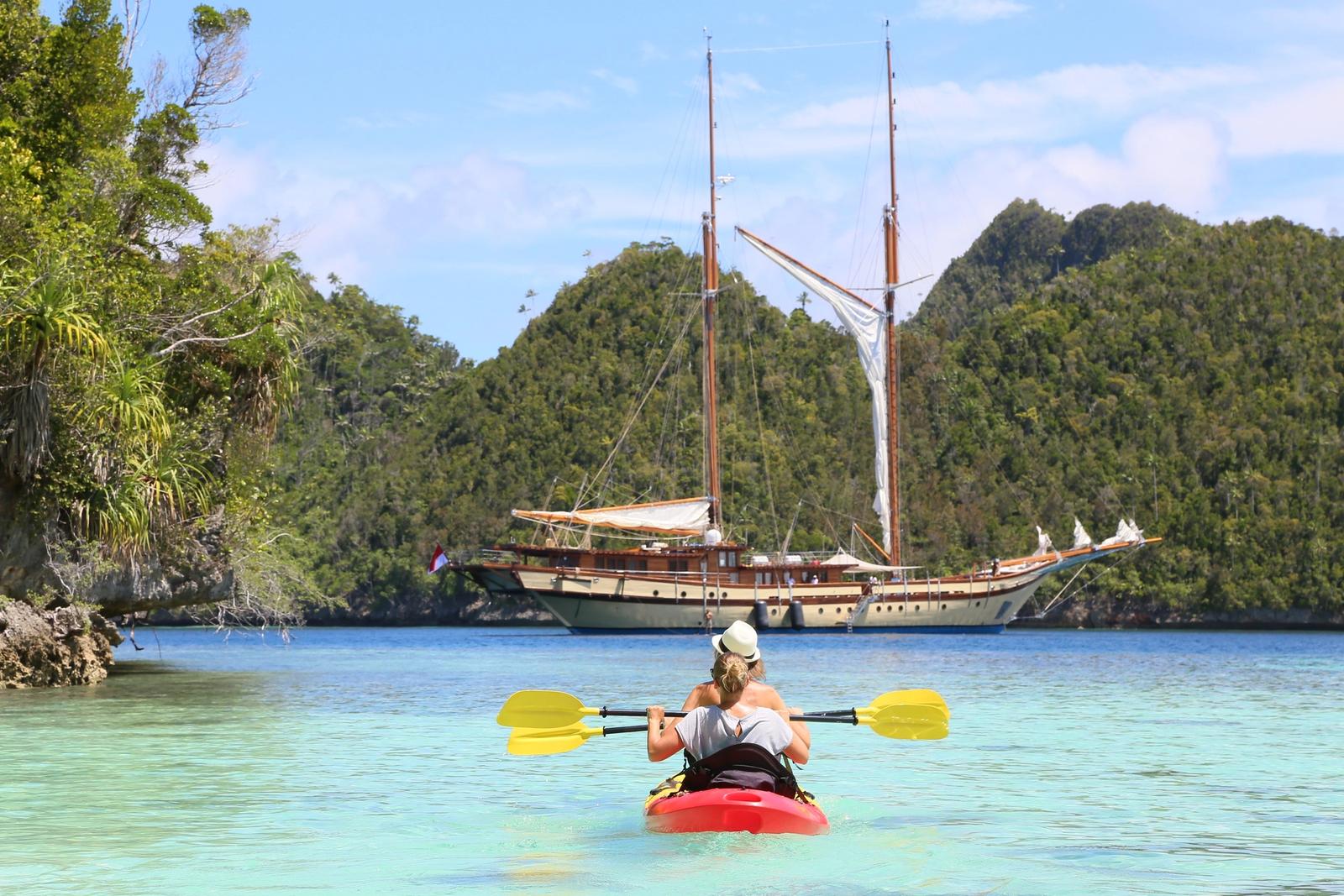A guest paddles a kayak beside the yacht between dives.