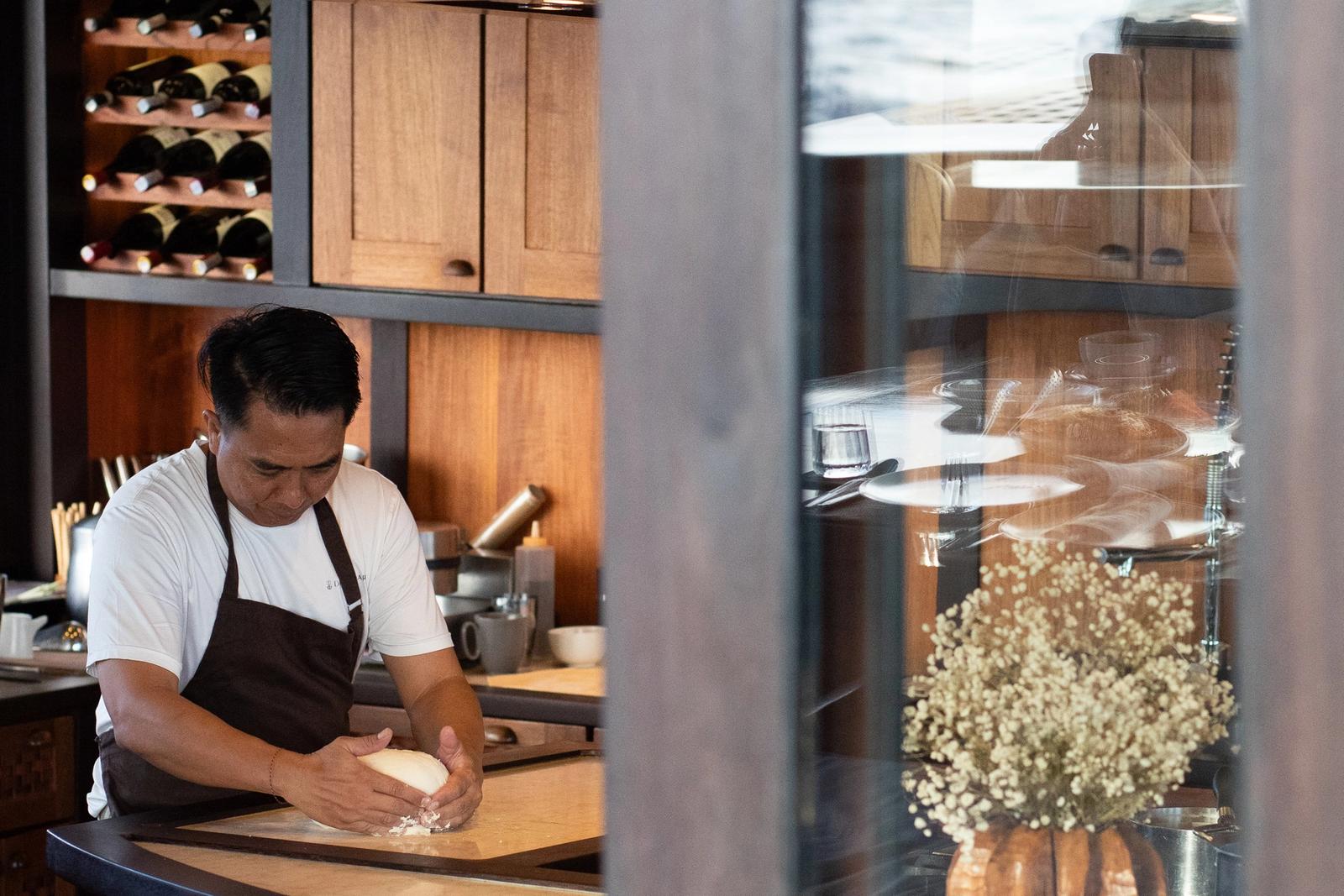 The chef kneads dough at the galley counter aboard Dunia Baru