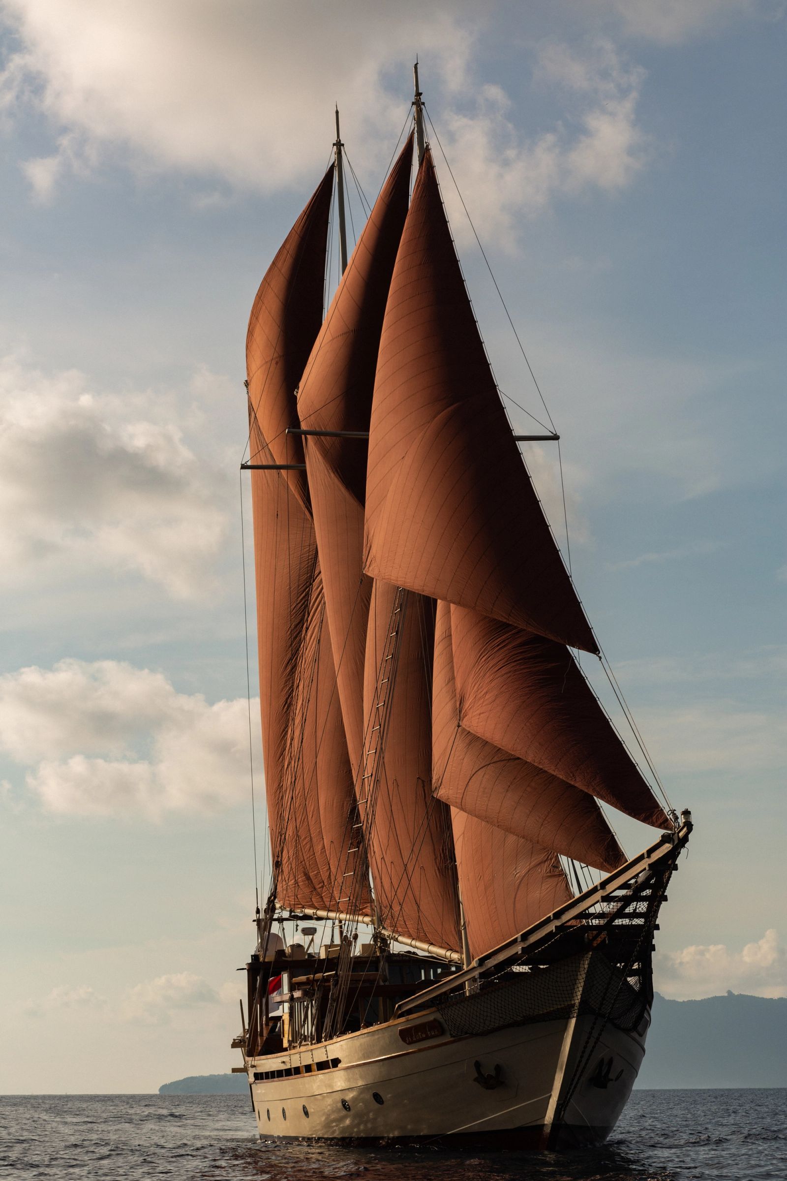 Si Datu Bua under red sails at dusk