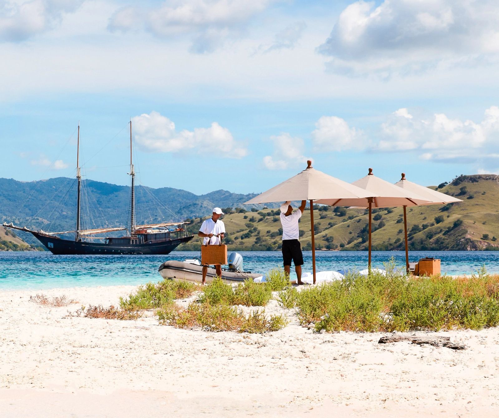Crew set up a beach picnic on white sand as Amandira lies at anchor beyond