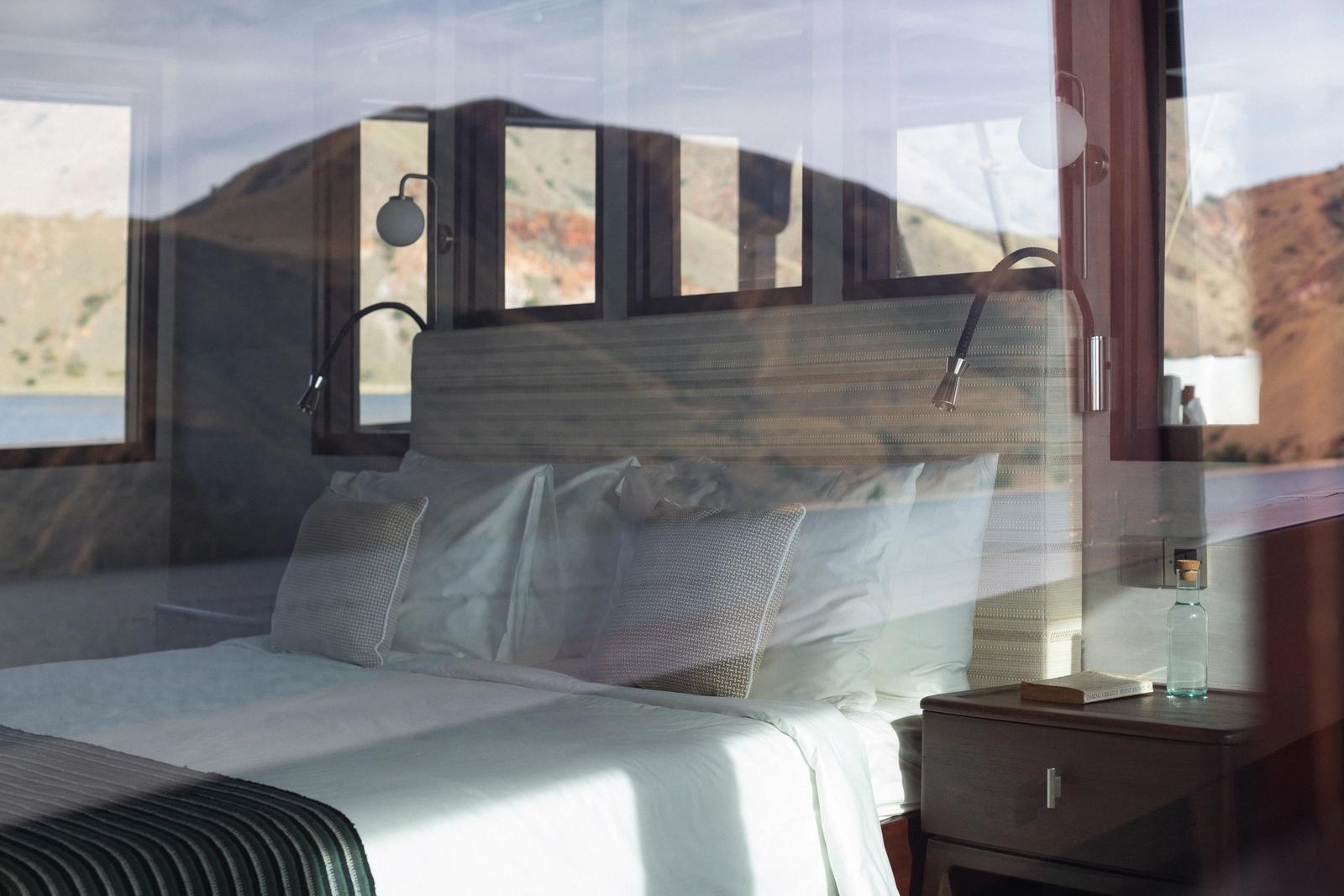 The main deck master cabin on Vela with the Komodo hills through the windows