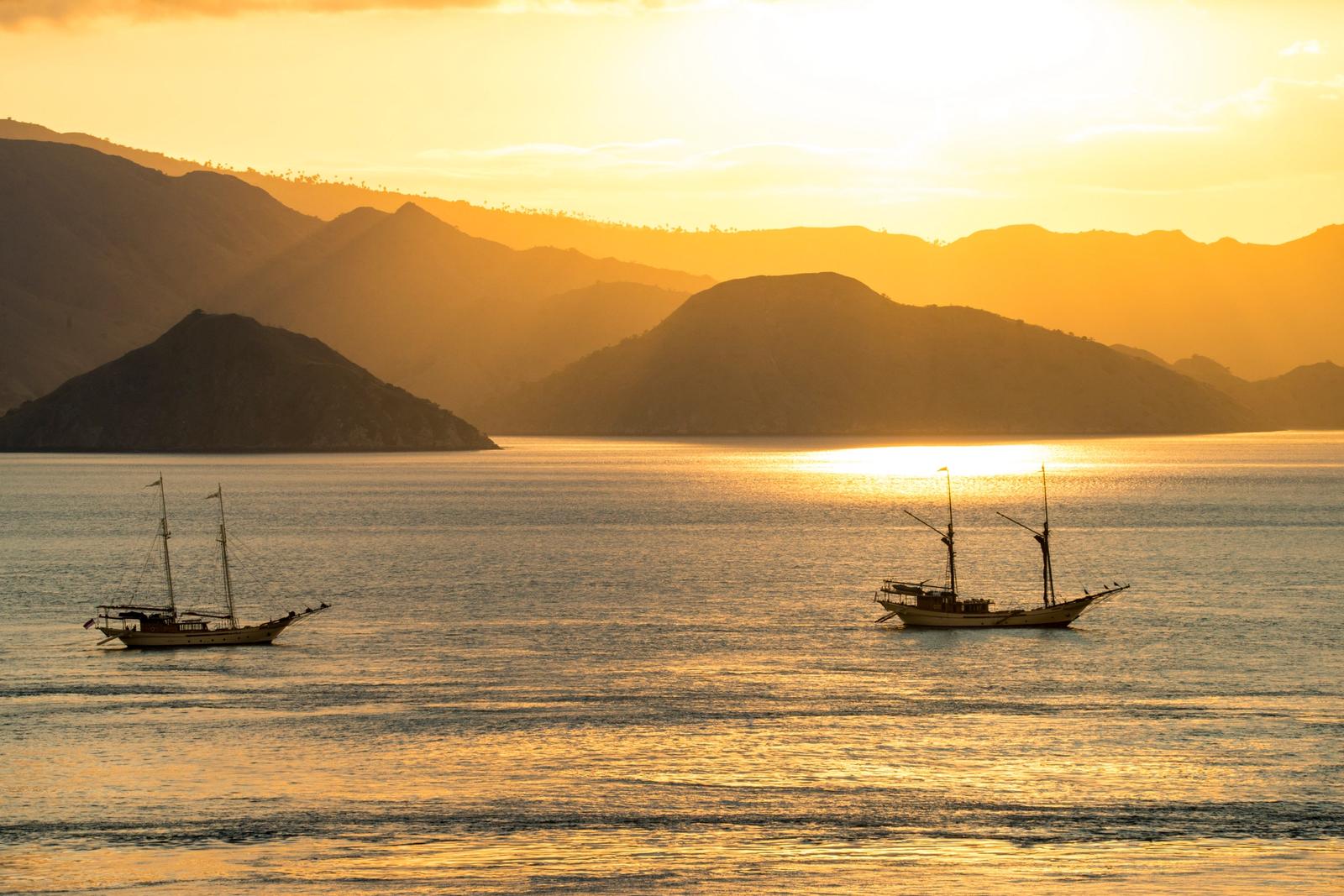 Two phinisis at anchor below hills at sunset