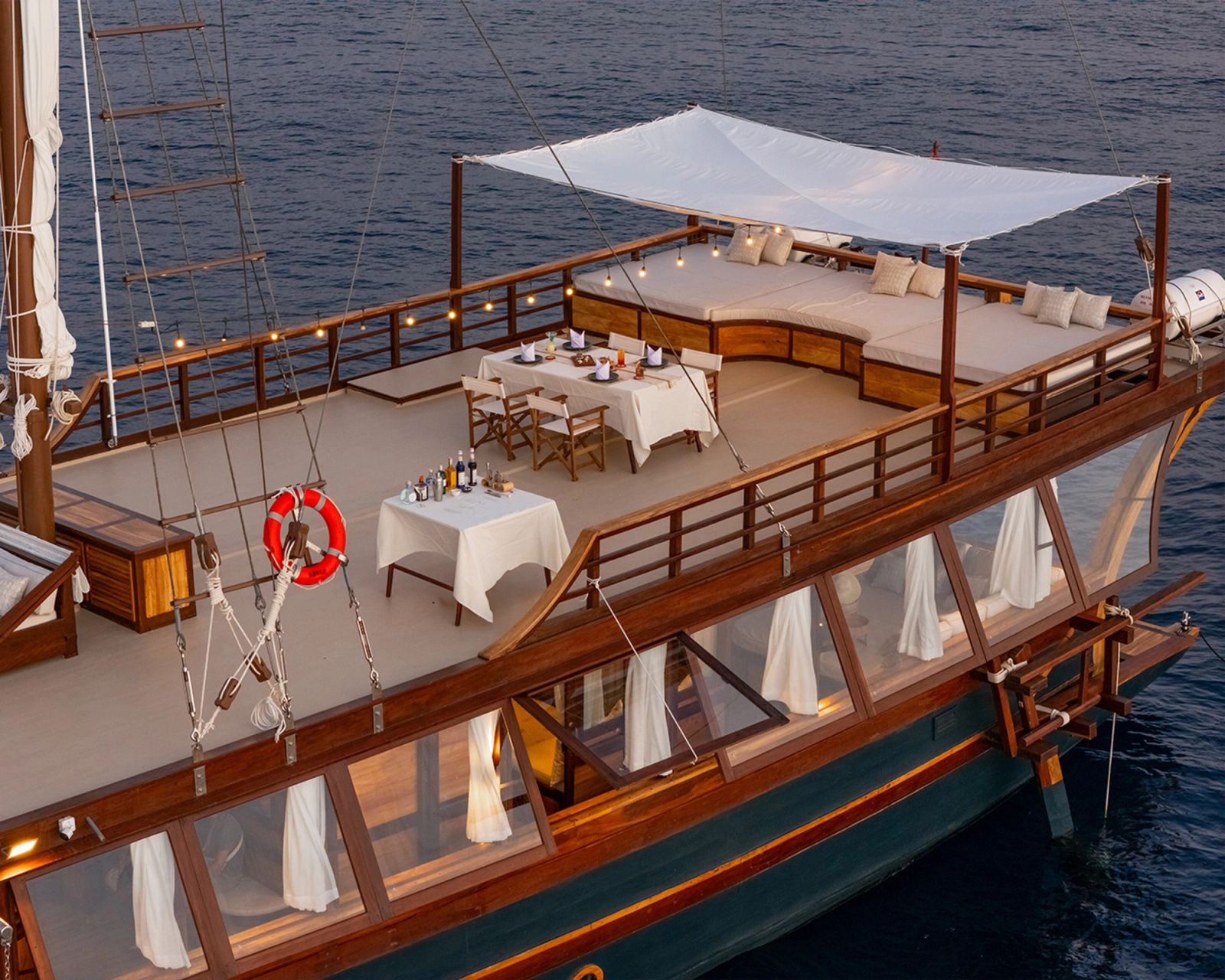 An aerial view of the main deck on Sanya with a dining table laid beneath the awning.
