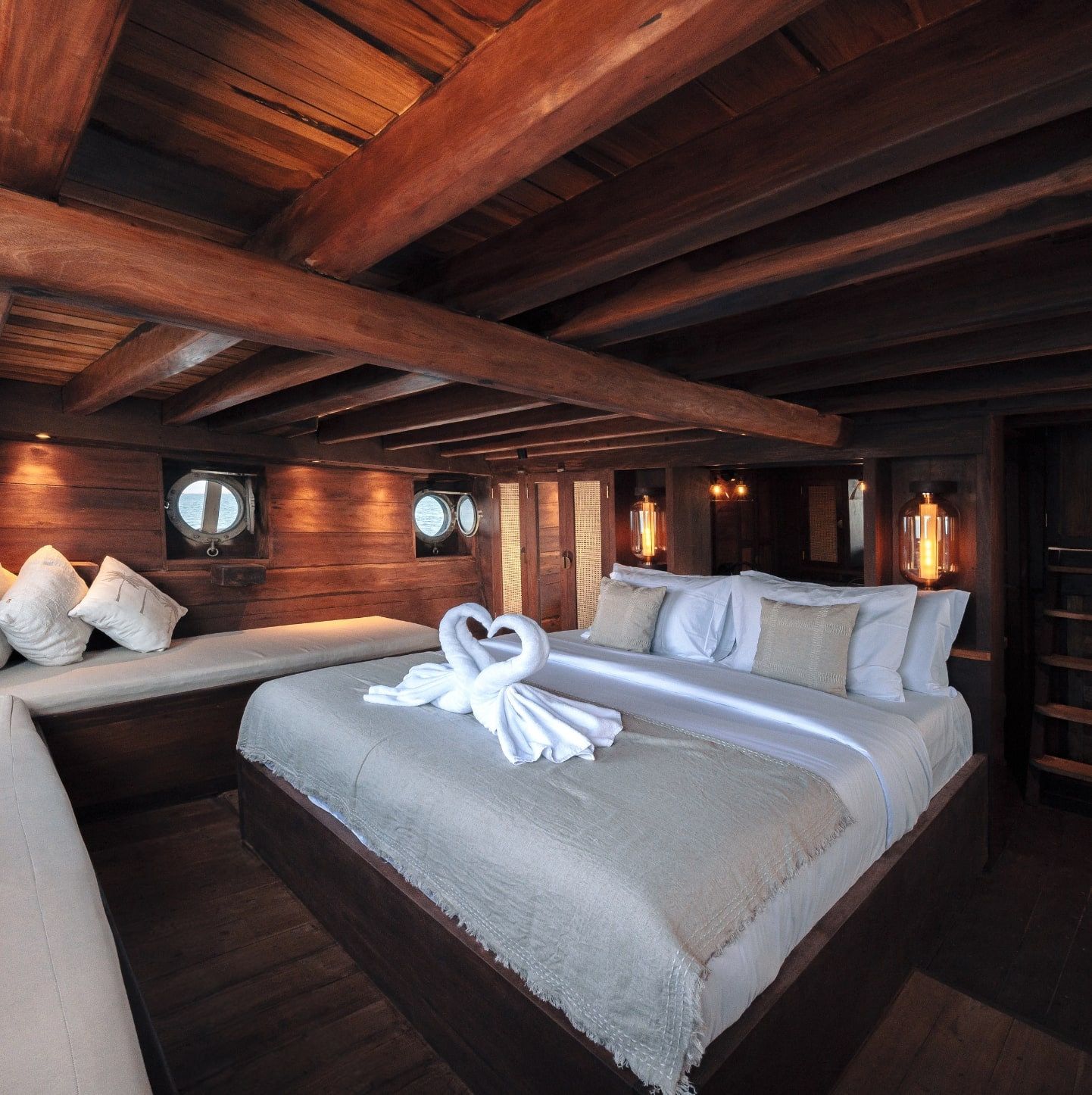 A guest cabin on Nataraja with folded towels on a wide bed.