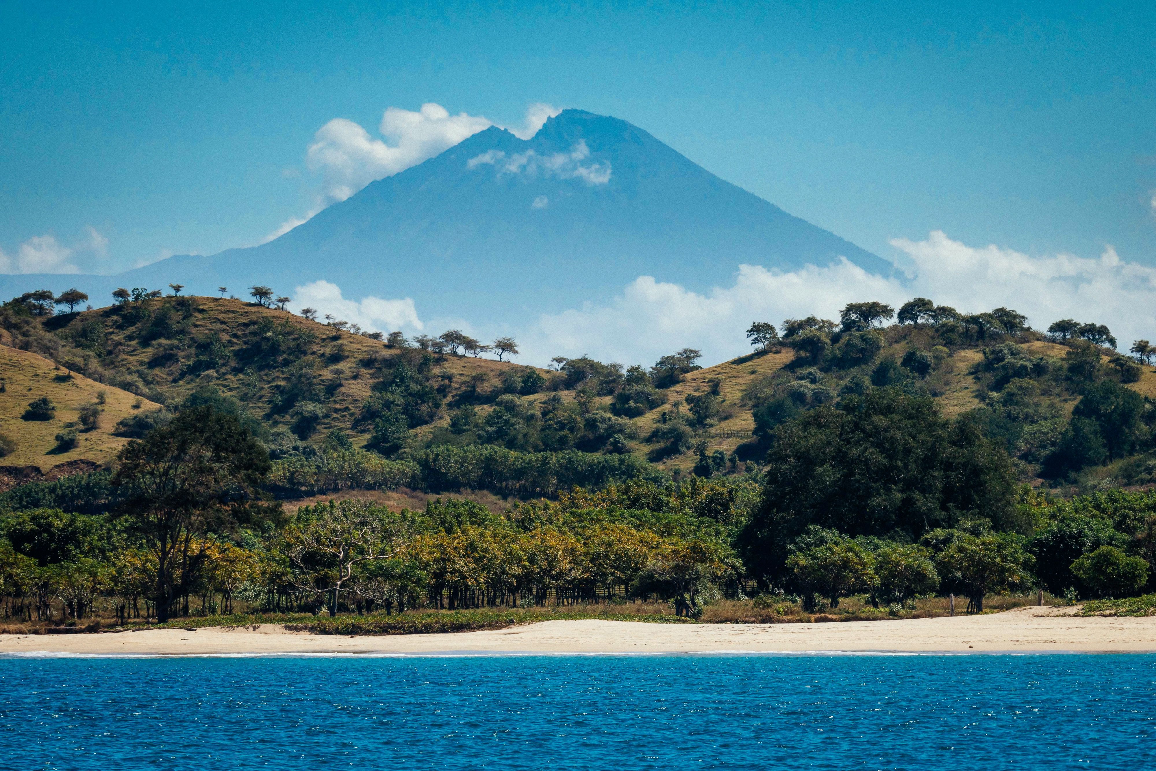 A white sand beach on the Sumbawa coast with a volcano rising beyond
