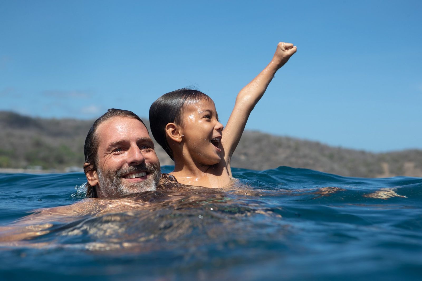 A father and child swimming beside Dunia Baru