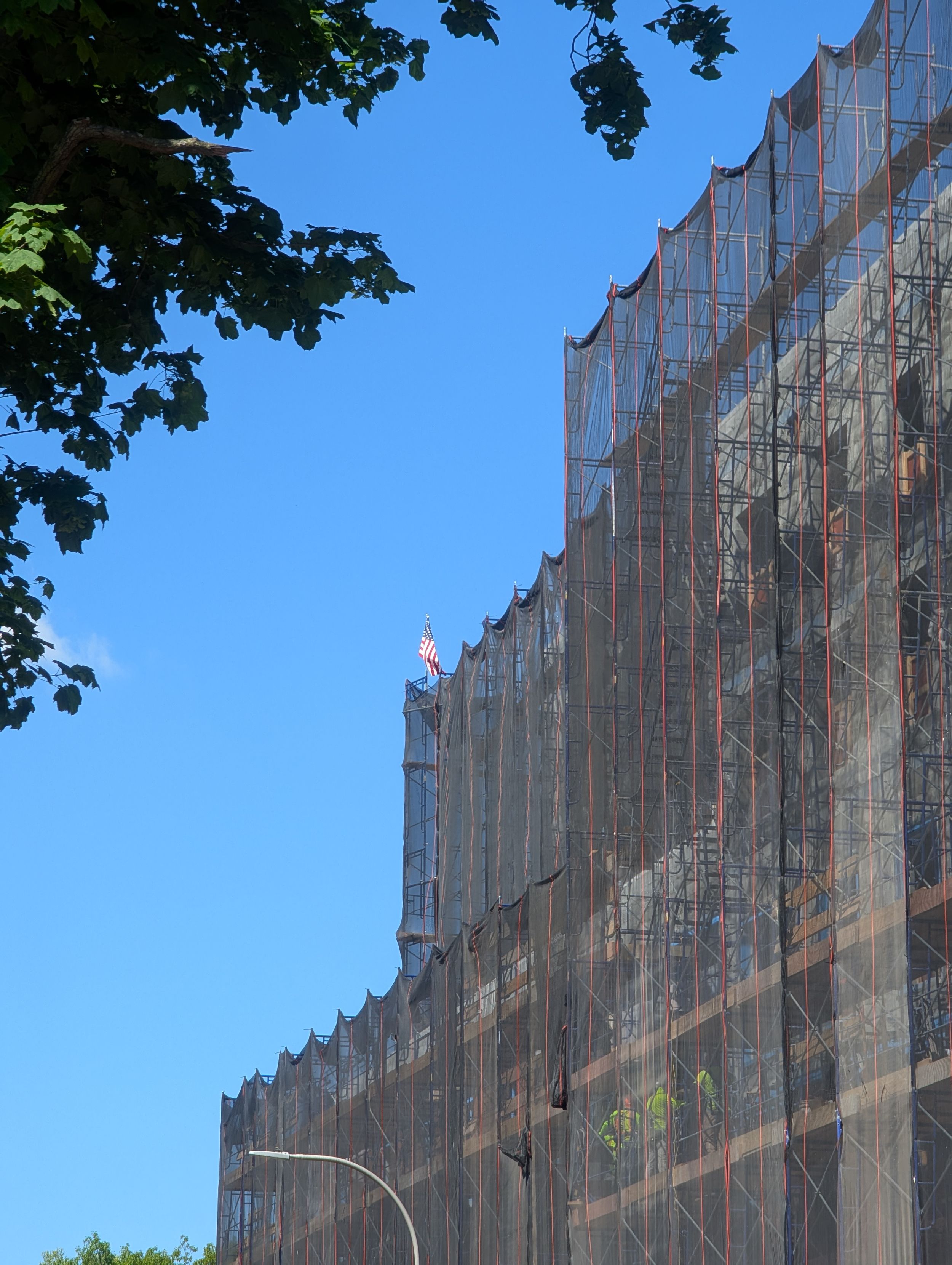 Detail of the scaffolding on the building's upper three setbacks, with an American flag on one of the parapets.