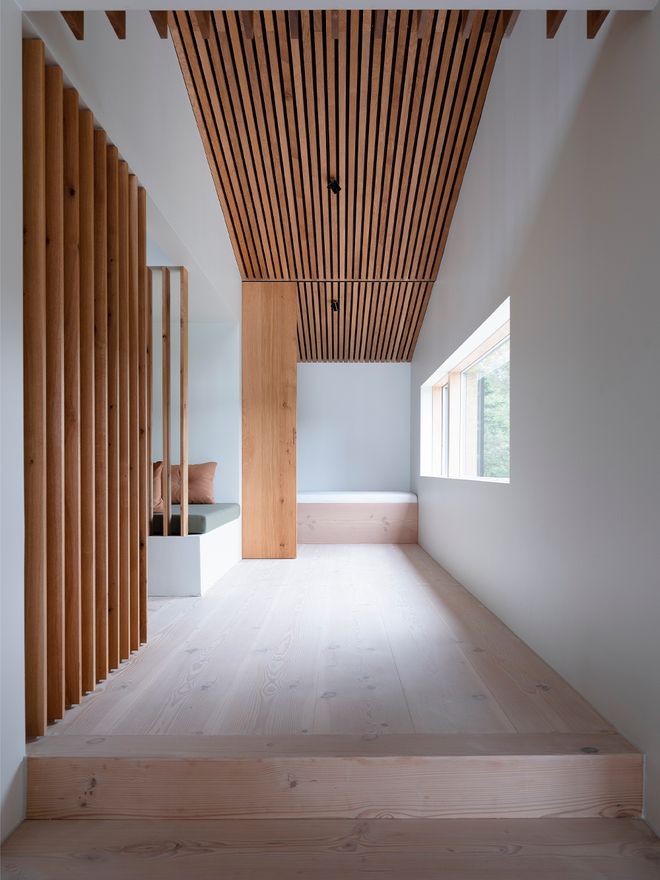 An image of the Holiday home by Þingvallavatn by KRADS architects: a leisure home located in Iceland in the middle of a picturesque scenery. This image features the buildings interior: an airy hallway with slatted details in the ceiling and walls.