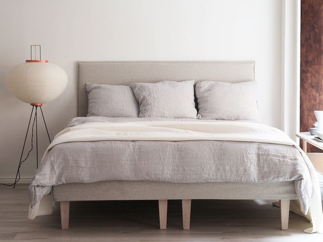 Vitra's Akari 10A floor lamp in a bedroom beside a bed.