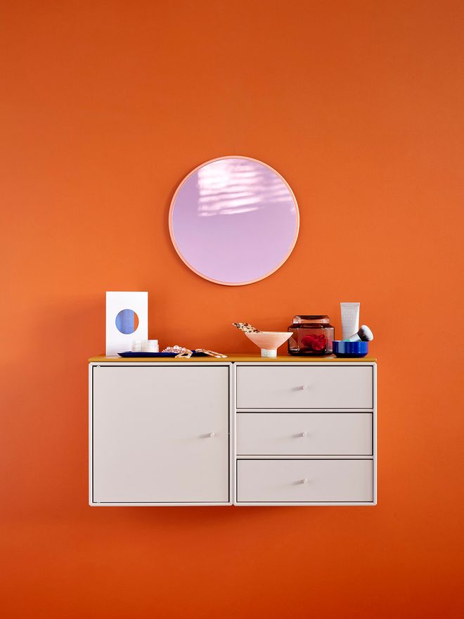 Montana Furniture's Montana Mini mirror in rhubarb, fixed on the wall together with Montana Mini storage modules.