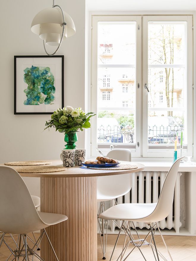 Ruokapöytä, jonka ympärilla valkoisia Eames DSR-tuoleja